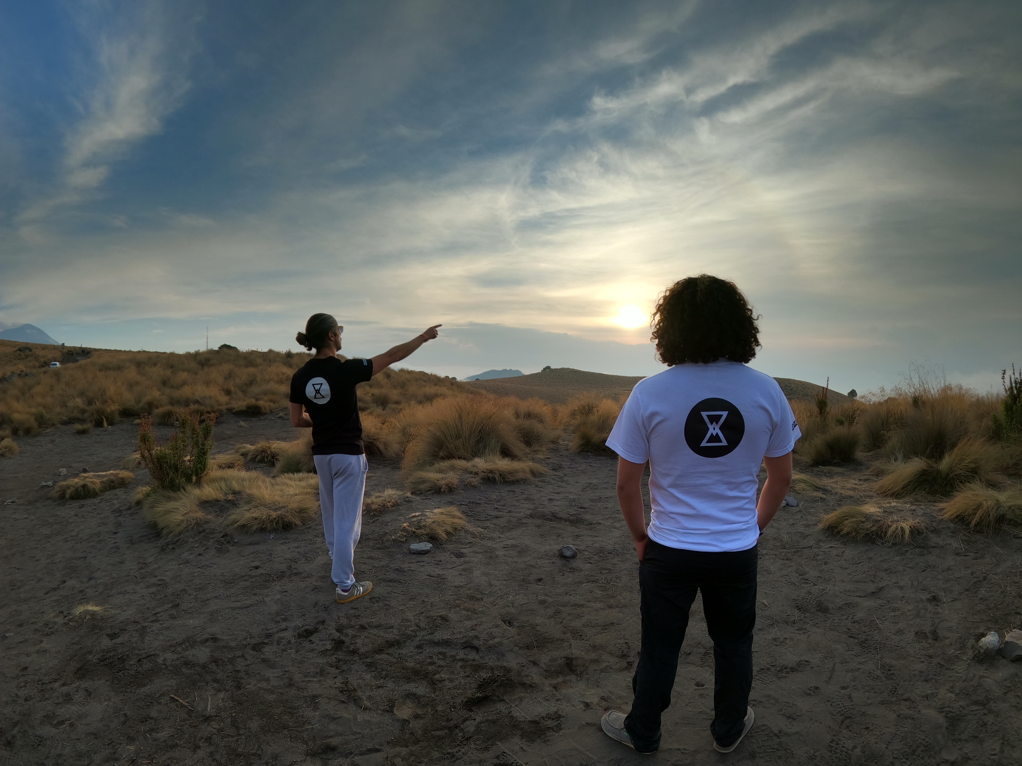 Dos personas con playera RPM Flow al atardecer volcánico