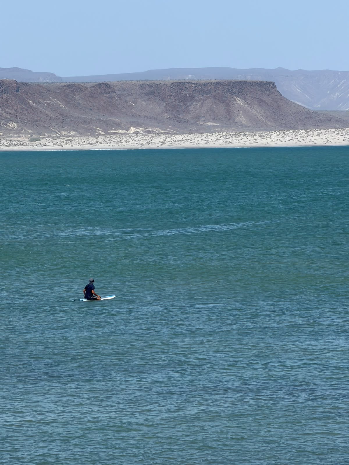 Fer en bici con tabla de surf en la orilla